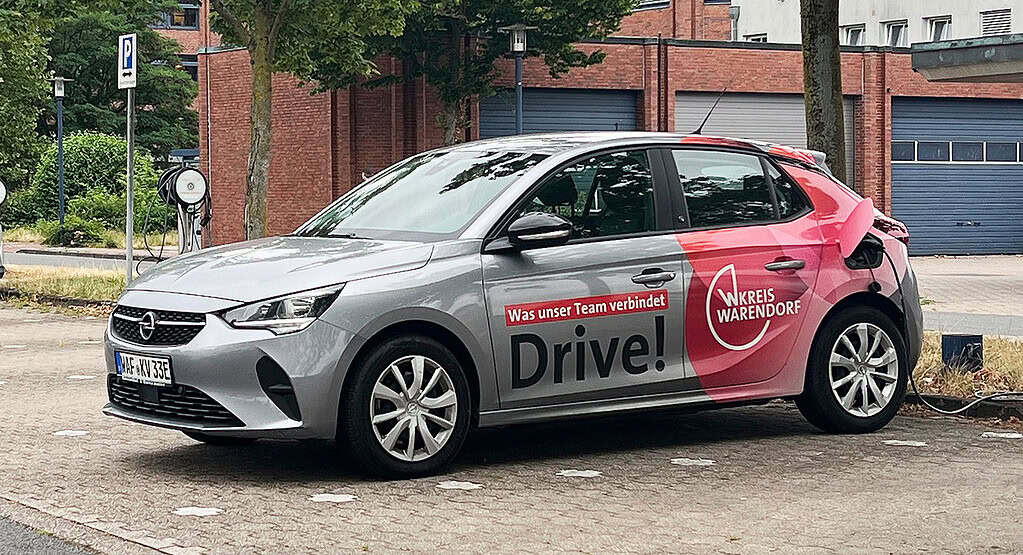 Fahrzeugbeklebung des Kreises Warendorf mit Motiven der Arbeitgeberkampagne an einer E-Ladestation.